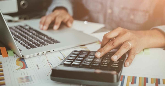 A person with a calculator and a computer