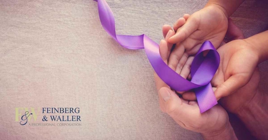 A set of adult hands holding a child's hands. The child is holding a purple ribbon, signifying domestic violence awareness