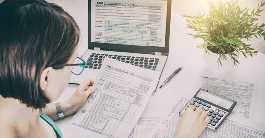 A woman working with a tax form and a calculator.