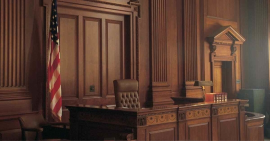 A courtroom. The judge's seat is empty