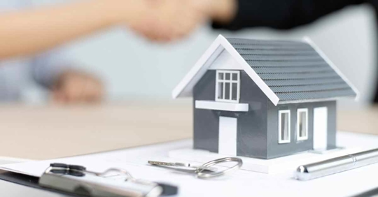 A miniature house resting on a pad of paper