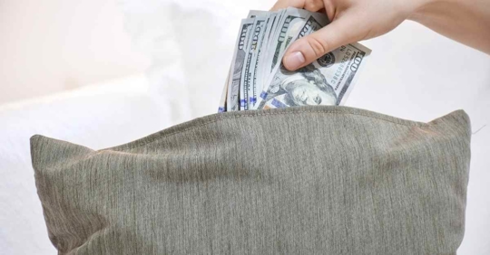 Someone stuffing money into a pillow case
