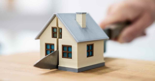 Someone cutting a miniature house in half