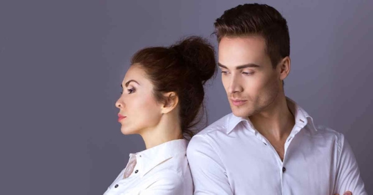 A man and woman standing back to back angrily against each other