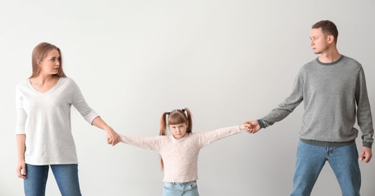 A father and mother each have their daughter by one hand. It seems as if they're pulling her to their respective side.