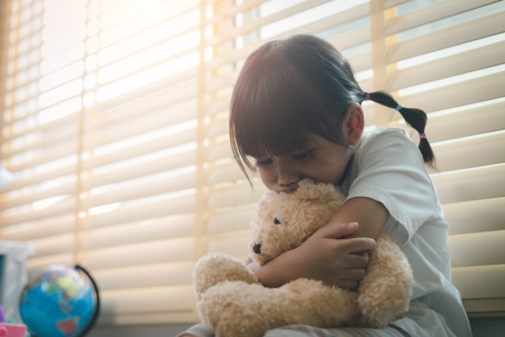 sad child hugging teddy bear