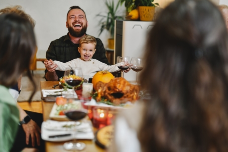 father and son laughing at Thanksgiving table