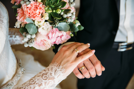 bride and groom holding hands and showing wedding rings